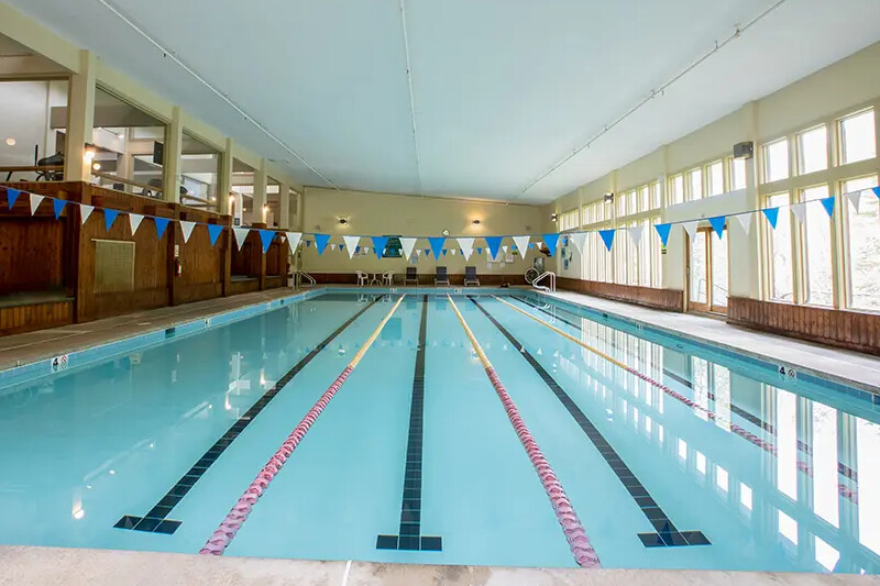 Indoor swimming pool with lanes, blue flags, and large windows for natural light.