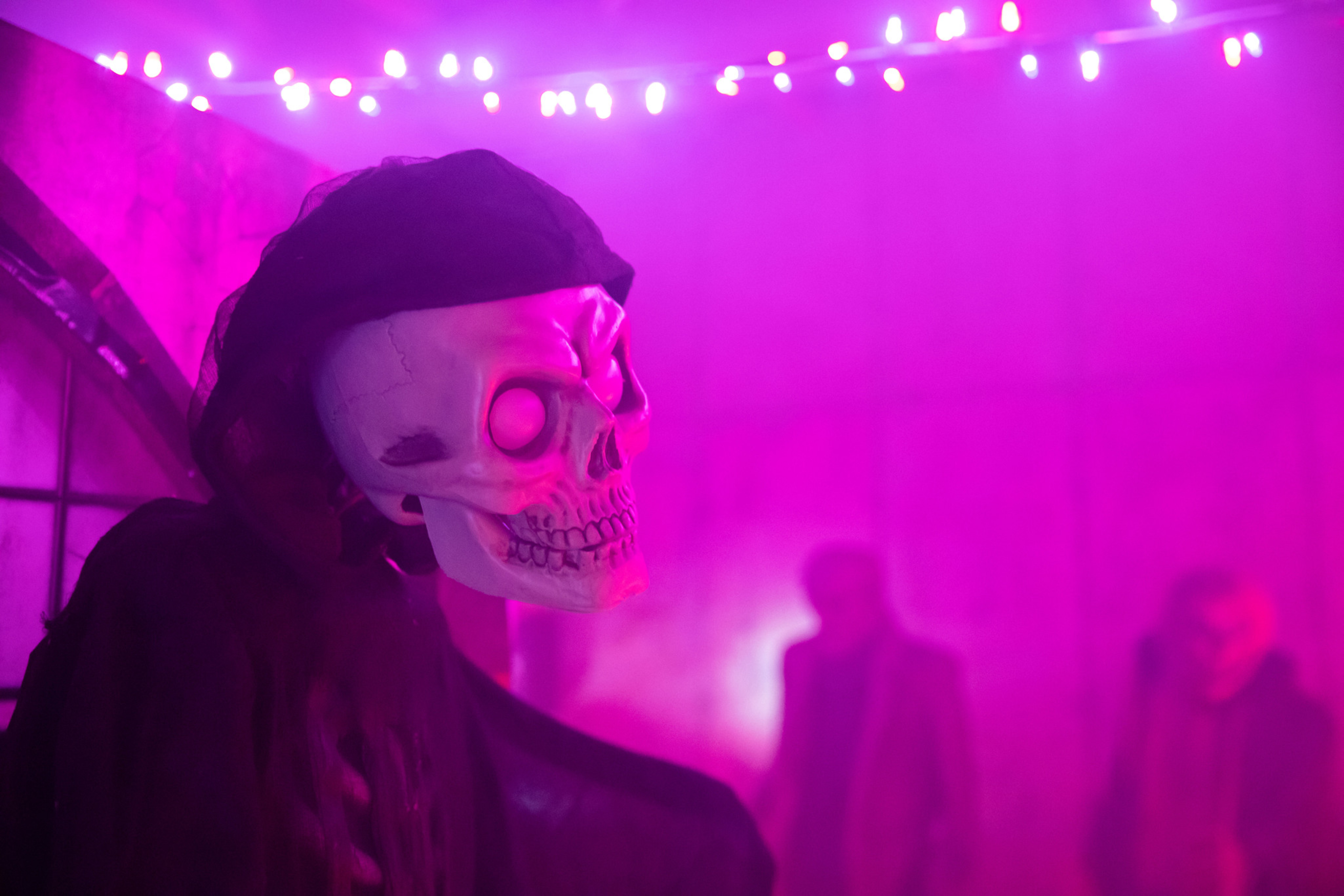 A skull figure in a dark cloak surrounded by purple mist and colorful lights.
