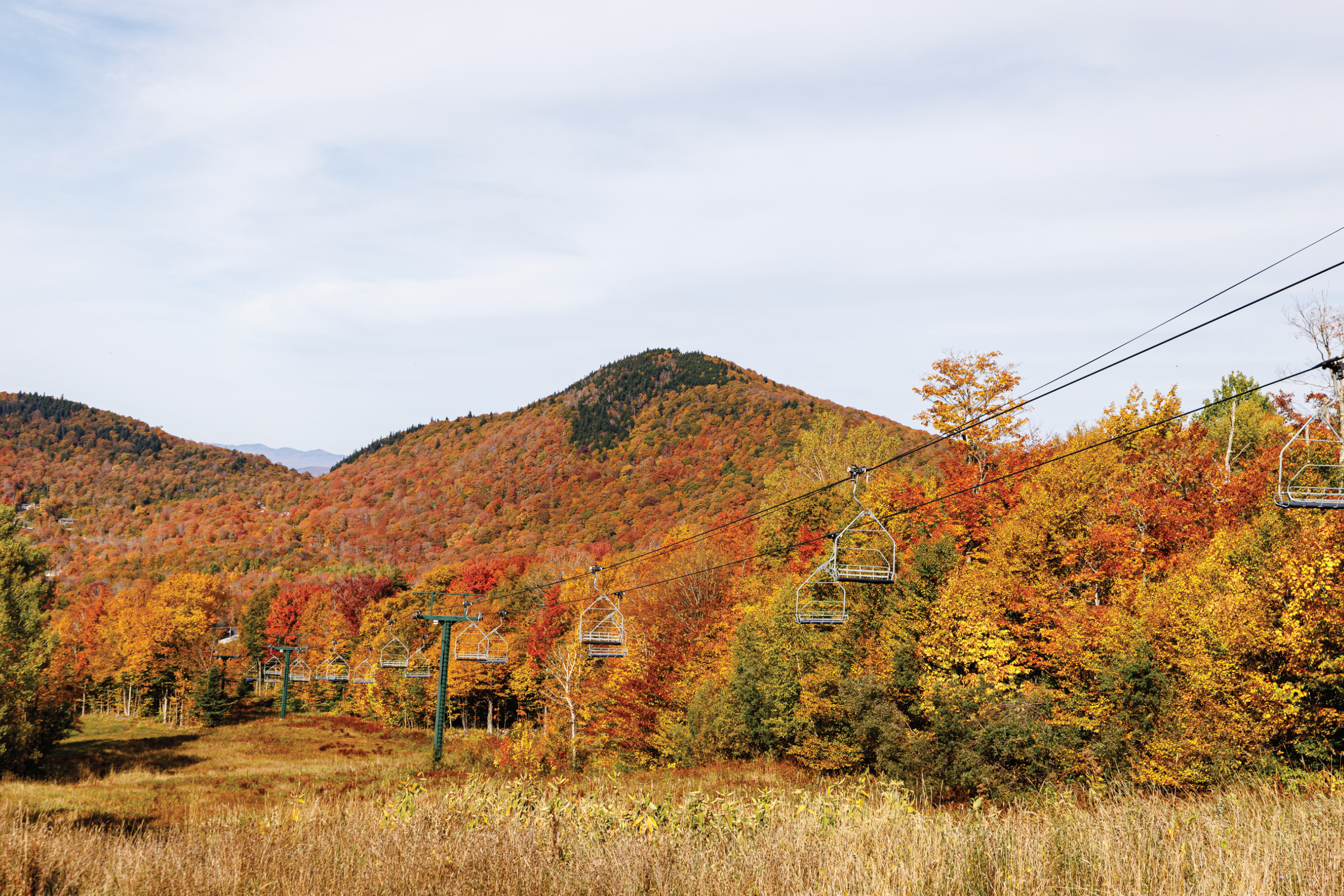 Autumn scenery with vibrant trees and a ski lift in the foreground.